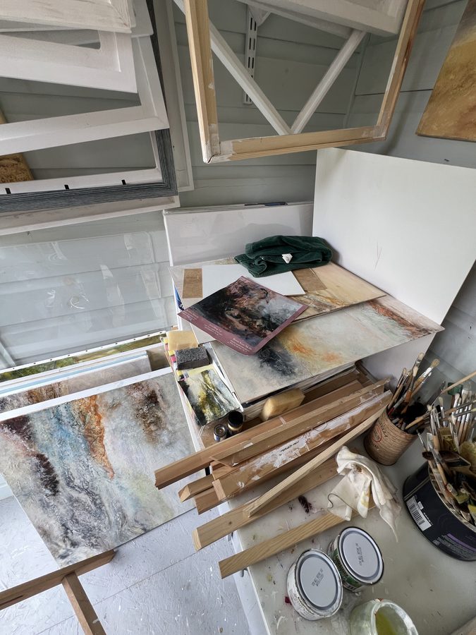 A corner of the studio with canvases, boards and brushes in pots